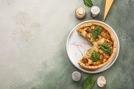 Mushroom pie with spinach leaves and champignons on green grunge table