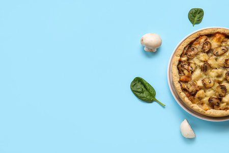 Mushroom pie with spinach leaves and champignons on blue background