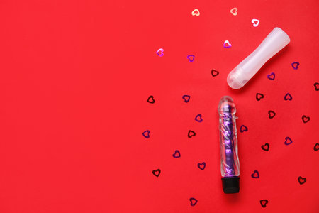 Bottle of lubricant and vibrator on red backgroundの写真素材