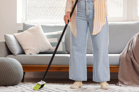 Mature woman sweeping floor in roomの写真素材
