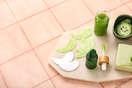 Board with cotton under-eye patches and cucumber slices on beige tile backgroundの写真素材