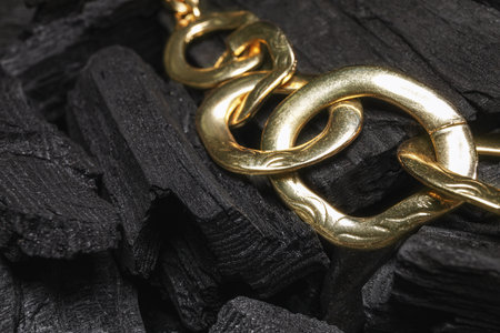 Golden necklace on black charcoal, closeupの写真素材