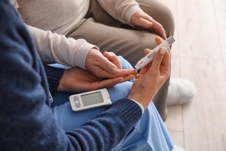 Young caregiver measuring sugar level of senior woman at home, closeupの写真素材