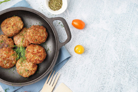 Frying pan with cutlets, dill and tomatoes on blue grunge table in kitchen