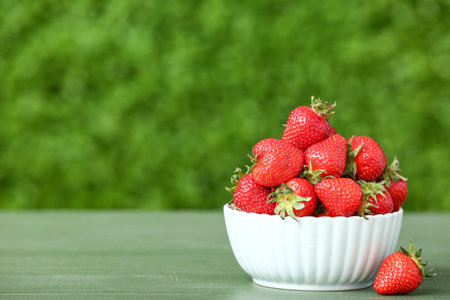 Bowl with fresh strawberry on green table outdoorsの写真素材