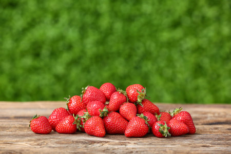 Heap of fresh strawberry on wooden table outdoors
