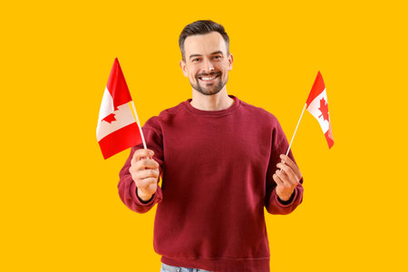 Handsome man with flags of Canada on yellow backgroundの写真素材