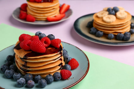 Plates with sweet pancakes and berries on color background, closeupの写真素材