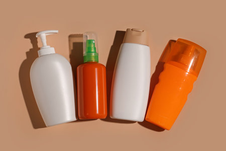 Different bottles of sunscreen cream on brown background
