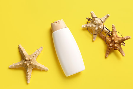 Creative composition with bottle of sunscreen cream and starfishes on yellow backgroundの写真素材