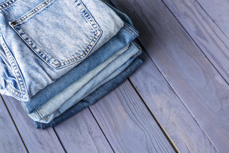 Different folded denim jeans on blue wooden backgroundの写真素材
