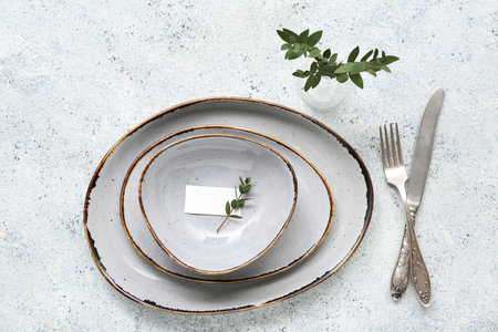 Stylish table setting with blank card and vase of plant branches on white grunge background