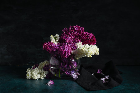 Beautiful lilac flowers in glass vase on dark grunge backgroundの写真素材