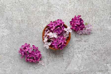Wooden bowl of beautiful fragrant lilac flowers on grunge gray backgroundの写真素材
