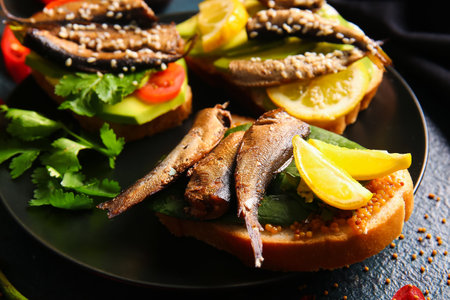 Plate of tasty sandwiches with canned smoked sprats on black backgroundの写真素材