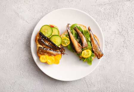 Plate of tasty sandwiches with canned smoked sprats on gray backgroundの写真素材