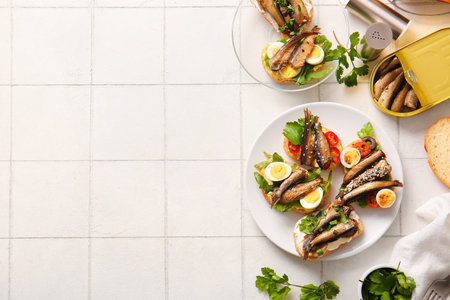 Plates of tasty sandwiches with canned smoked sprats on white tile backgroundの写真素材