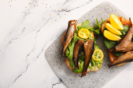 Board of tasty sandwiches with canned smoked sprats on white marble backgroundの写真素材