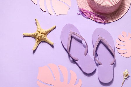 Flip flops with hat, sunglasses and palm leaves on lilac backgroundの写真素材