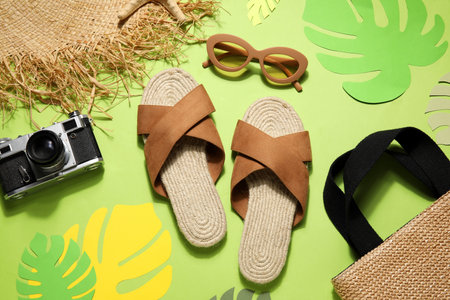 Sandals with sunglasses, camera and hat on green backgroundの写真素材