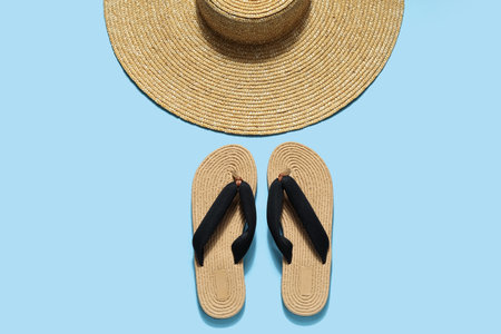 Wicker hat with flip flops on pale blue backgroundの写真素材