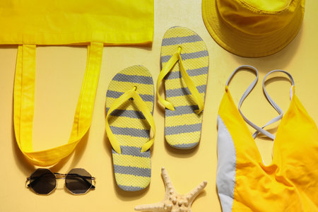 Flip flops with beach accessories on yellow backgroundの写真素材