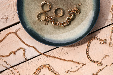 Plate with beautiful golden jewelery on wooden backgroundの写真素材