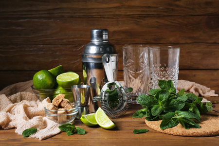 Glasses, shaker, strainer and ingredients for preparing mojito on wooden backgroundの写真素材