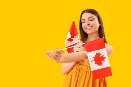 Young woman with flags of Canada on yellow backgroundの写真素材
