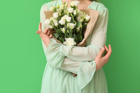 Young woman with bouquet of beautiful eustoma flowers on green backgroundの写真素材