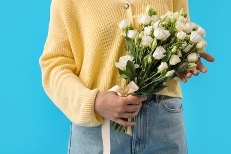Young woman with bouquet of beautiful eustoma flowers on blue backgroundの写真素材
