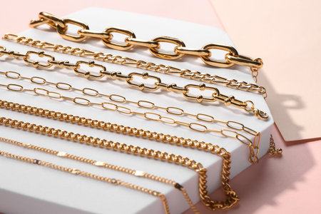 Decorative stand with golden bracelets and necklaces on color background