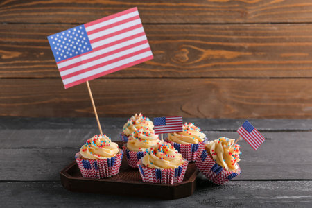 Tray tasty patriotic cupcakes with flags of USA on black table near brown wooden wall. american independence dayの写真素材
