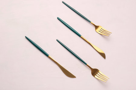 Golden forks and knives with green handles on white backgroundの写真素材