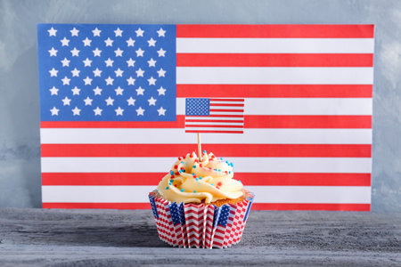 Tasty patriotic cupcake on gray wooden table against USA flagの写真素材