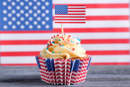 Tasty patriotic cupcake on gray wooden table against USA flagの写真素材