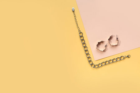 Beautiful silver bracelet and earrings on color background