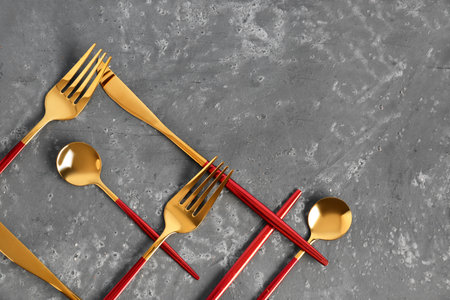 Golden cutlery with red handles on dark backgroundの写真素材