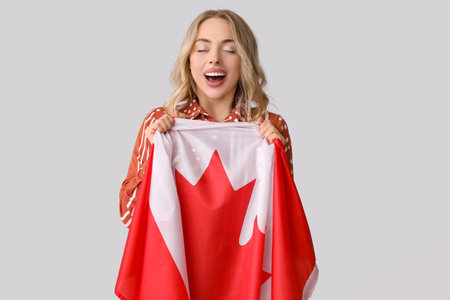 Young woman with flag of Canada on light backgroundの写真素材