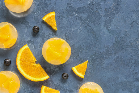 Fresh blueberry, orange and pieces frozen in ice on blue backgroundの写真素材