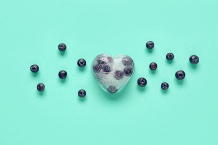 Ripe blueberry frozen in ice with fresh berries on blue backgroundの写真素材