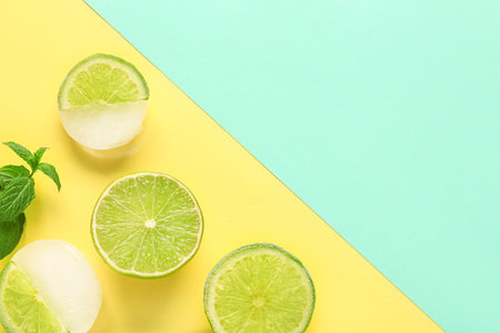 Fresh lime and slices frozen in ice on color background