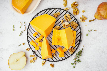 Cooling rack with pieces of tasty cheddar cheese on light backgroundの写真素材