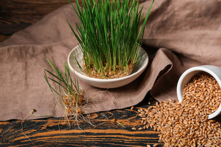 Bowl with fresh wheatgrass and kitchen towel on brown wooden tableの写真素材