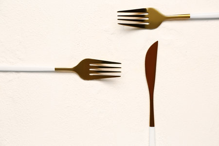 Golden forks and knife with colored handles on white backgroundの写真素材