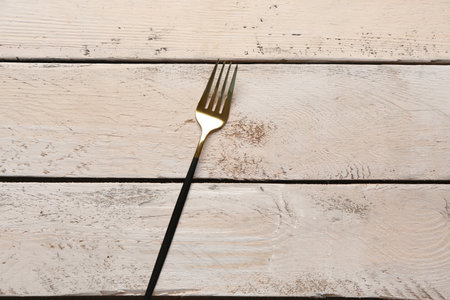 Golden fork with black handle on white wooden backgroundの写真素材