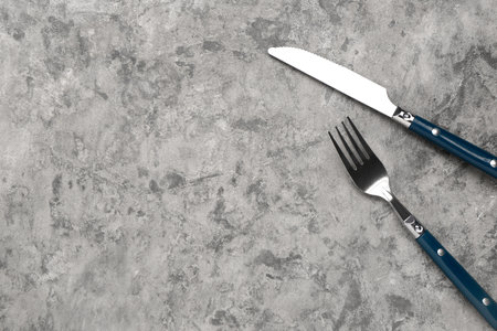 Stainless steel fork and knife with blue handles on gray backgroundの写真素材