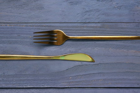 Golden fork and knife on blue wooden background