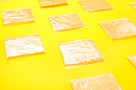 Slices of tasty processed cheese on yellow background