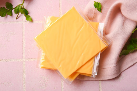 Slices of tasty processed cheese with herbs on pink tile background